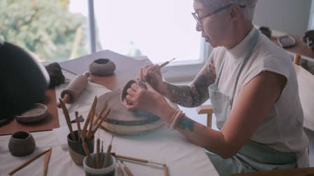 Asian elderly woman enjoying pottery work at home. A female ceramicist is making new pottery in a studio.の写真素材