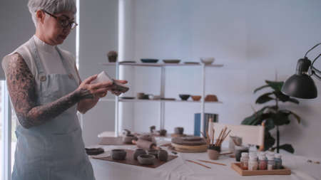 Asian elderly woman enjoying pottery work at home. A female ceramicist is making new pottery in a studio.の写真素材