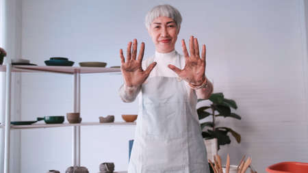 Asian elderly woman enjoying pottery work at home. A female ceramicist is making new pottery in a studio.の写真素材