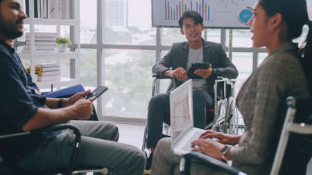 Confident business man in wheelchair presenting during business meeting with colleagues.の写真素材