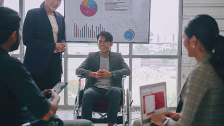 Confident business man in wheelchair presenting during business meeting with colleagues.の写真素材
