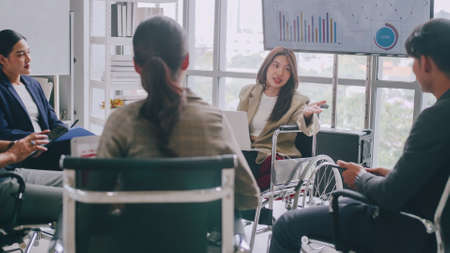 Confident business woman in wheelchair presenting during business meeting with colleagues.の写真素材