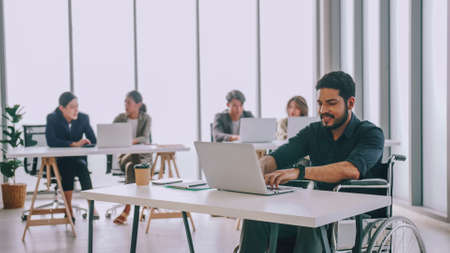 A disabled company employee is able to work happily with colleagues in the office.の写真素材