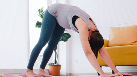 Beautiful young Asian pregnant woman in sportswear is doing yoga at home.の写真素材