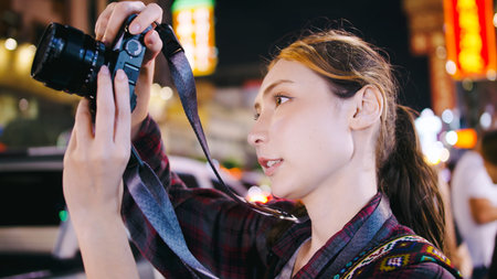 A female tourist enjoys taking photos of the night view of Yaowarat Road or Chinatown in Bangkok,...