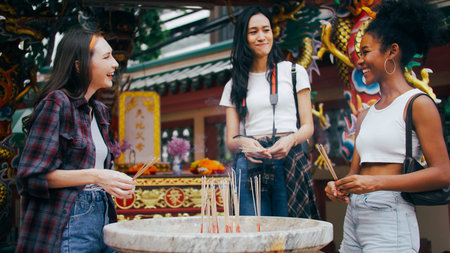 A group of multi-ethnic female friends praying at a Chinese shrine in Bangkok, Thailand.