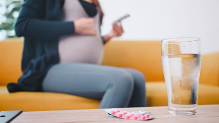 Young pregnant woman taking medicine at home.の写真素材