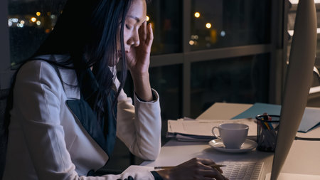 Stressed young Asian businesswoman working overtime at the office.の写真素材