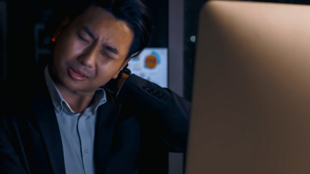 Stressed young Asian businessman working overtime at the office.の写真素材
