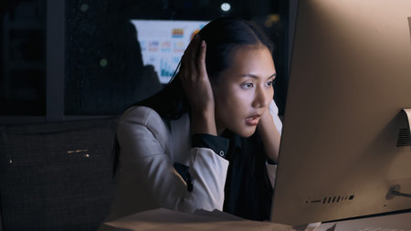 Stressed young Asian businesswoman working overtime at the office.