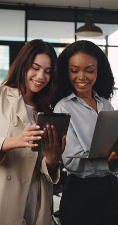 Two young beautiful business women  working together in office.