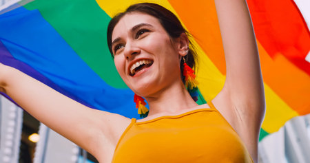 A young woman waves a rainbow flag, a symbol of homosexuality, during a pride parade.の写真素材