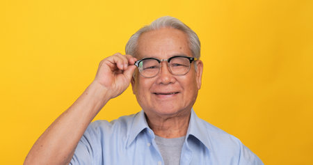 Close up, portrait of older man smiling and looking at the camera. Isolated on yellow background in the studio.の写真素材