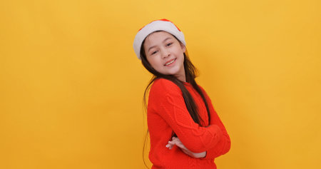 Cute little girl wearing a Christmas dress. Isolated on yellow background in studio.の写真素材