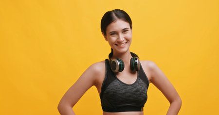 Portrait of a young woman wearing sportswear. Isolated on yellow background in studio.