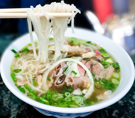 Bowl of Vietnamese pho noodle soup with rare beef, tendon, tripe and brisket served with onions, scallions and cilantro の写真素材
