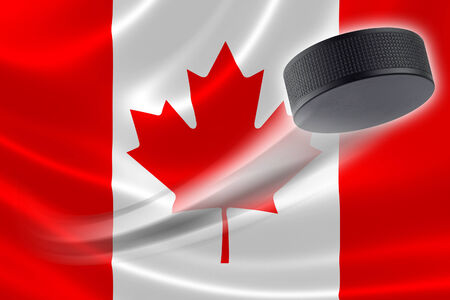 Hockey puck streaks across the flag of Canada, where the country is one of the world's major ice hockey nations.の写真素材