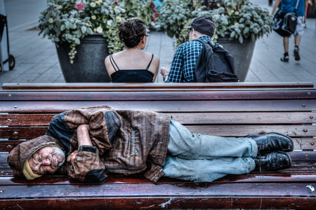 Montreal, Canada - Aug 20, 2012: A homeless man sleeps on a park bench in Montreal, QC, Canada. Homelessness has become a major concern in Canada. It prompted the government to commit $600 million over five years starting April 2014 to renew and refocus tのeditorial素材