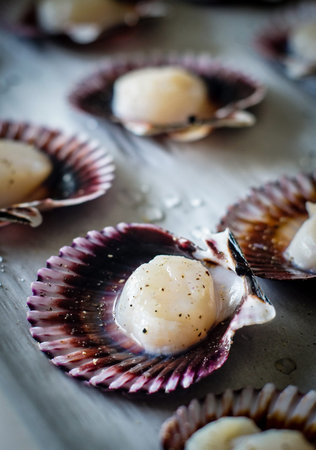 Seafood scallops seasoned with salt and pepper ready to be cooked. 
