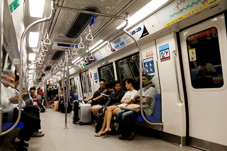 Commuters inside the cabin of a metro train known as Mass Rapid Transit MRT. Singapore's extensive train system spans almost the entire country.のeditorial素材