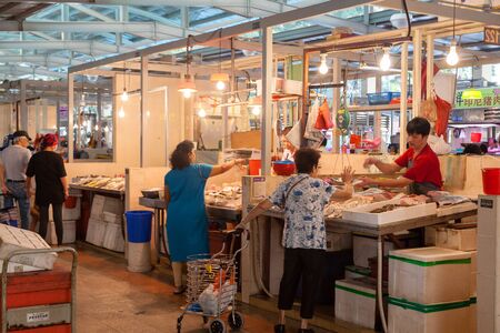 A fishmonger at a local wet market in Singapore helping a customer. For local residents, a wet market is the place to buy groceries and the freshest produce.のeditorial素材