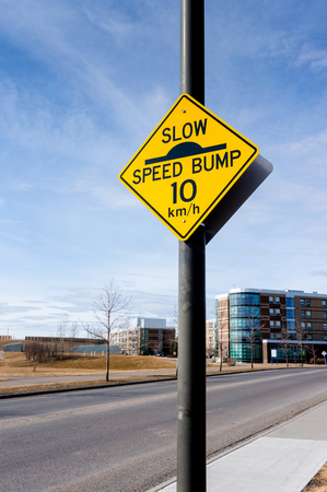A slow down traffic sign in a residential area indicating a speed bump and a 10 km per hour driving speed.の写真素材