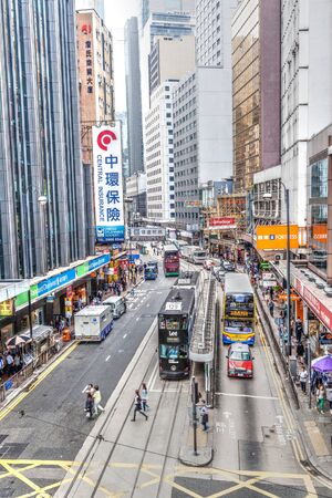 Hong Kong, China - March 31, 2015:  Historic double-decker trams share the road with other traffic vehicles in the busy downtown Central District of Hong Kong Island. The business hub of the city, Central bustles with shoppers and tourists because of its のeditorial素材