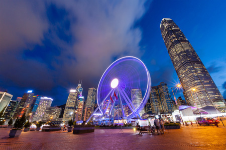 Sunset on Hong Kong's vibrant night life at Central Pier near Victoria Harbour with the Observation Wheel in motion and the downtown financial district in the background.のeditorial素材