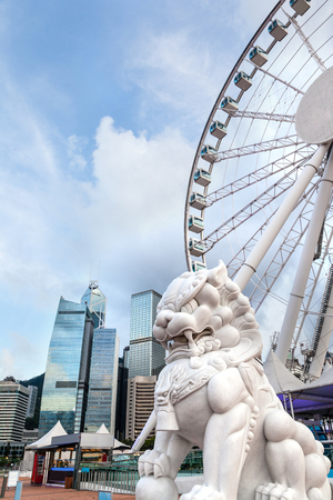 A traditional Chinese guardian lion statue with Hong Kong's skyline at Central Pier, Victoria Harbor, on Hong Kong Island. Common and popular in Chinese culture, the symbolic lion possesses mythical protective benefits of luck and prosperity.のeditorial素材