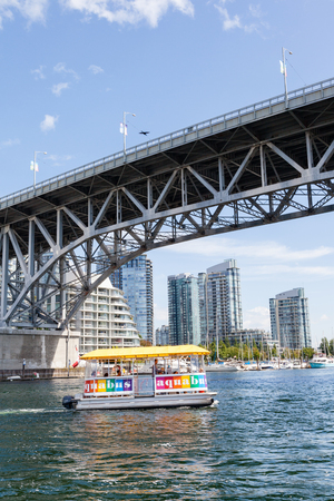 VANCOUVER - AUG. 16, 2017: Visitors to Granville Island taking the Aquabus water taxi across False Creek harbor with the Granville Street Bridge and Vancouver's Yaletown skyline in the background.のeditorial素材