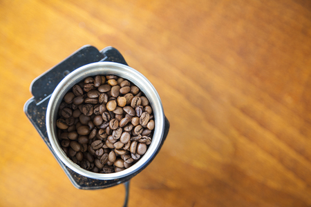 Mocha coffee beans poured onto an electric coffee grinder ready for grinding with copy space. Top view.の写真素材