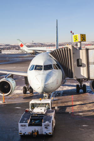 CALGARY, CANADA - DEC. 4, 2014: An Air Canada plane connected to a jet bridge waiting and being serviced on the tarmac of Calgary International Airport. Vertical orientation.のeditorial素材
