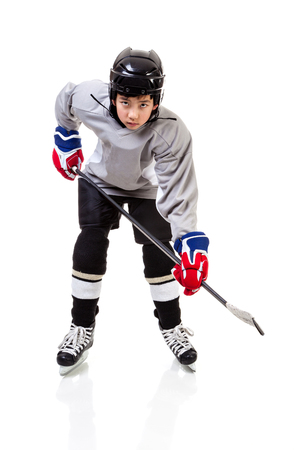 Portrait of junior ice hockey player on the alert with full equipment and uniform posing for a shot with a puck. Isolated on white background.の写真素材