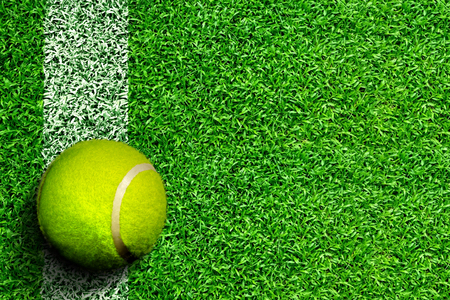 High angle view of tennis ball on grass court with white line marking and copy space. Line represents tennis court boundary sidelines, service line, or baseline.の写真素材