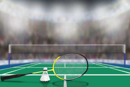 Low angle view of badminton racket and shuttlecock in arena with sports fans in the stands and copy space. Focus on foreground with deliberate shallow depth of field on background.の写真素材