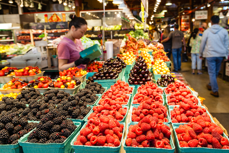 VANCOUVER - AUG 16, 2017: A vendor prepares her fruits for sale at the Granville Island Market. Granville Island is located across False Creek from Downtown Vancouver. Selective focus on fruits.のeditorial素材