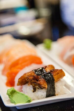 Focus on freshwater eel unagi nigiri sushi with wasabi on the side and shallow depth of field on background for copy space.の写真素材