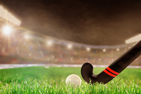 Field hockey stick and ball on grass in brightly lit outdoor stadium with focus on foreground and shallow depth of field on background. Deliberate lens flare and copy space.の写真素材