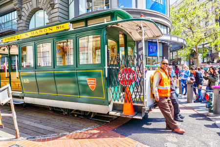 SAN FRANCISCO - APR 2, 2018: Workers rotate a cable car at the Powell and Market street turntable to pick up a crowd of passengers. A San Francisco historic icon, it's the world's last manually operated cable car system.のeditorial素材
