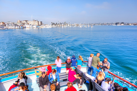 NEWPORT BEACH, CA, USA - MAR 29, 2018: Tourists on the stern of a boat leaving Balboa pier in Southern California on a sightseeing cruise out to sea, a popular activity among vacationers.のeditorial素材