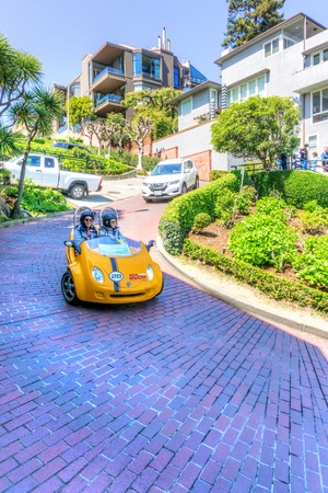 SAN FRANCISCO - APR 2, 2018: Tourists drive down crooked Lombard Street on a GoCar, a scooter created for tourists as a different way to explore a city. It is the worldâs first-ever GPS-guided Storytelling car.のeditorial素材
