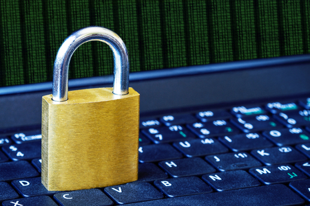 Golden padlock on computer laptop keyboard with binary data running and copy space. Concept of Internet security, data privacy, cybercrime prevention. Selective focus.の写真素材