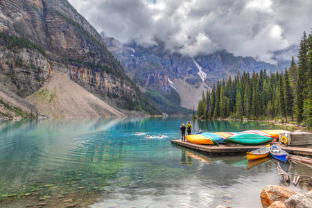 LAKE LOUISE, CANADA - AUG 21, 2014: Visitors taking a cold dip in Moraine Lake near Lake Louise in Banff National Park as friends took pictures. Heavy clouds descend on the Valley of Ten Peaks in the background.のeditorial素材