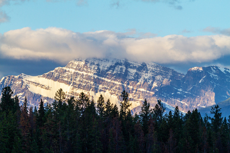 Close up of Mount Edith Cavell in Jasper National Park with the glow of the morning sun and low clouds descending on the summit.の写真素材