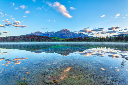 Sunrise over Patricia Lake in Jasper National Park with Pyramid Mountain in the background and misty fog on the water's surface. Calm waters create serene reflections.の写真素材