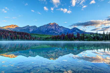 Sunrise over Patricia Lake in Jasper National Park with Pyramid Mountain in the background and misty fog on the water's surface. Calm waters create serene reflections.の写真素材