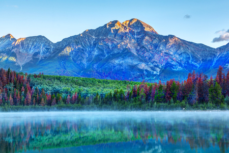 Sunrise over Patricia Lake in Jasper National Park with Pyramid Mountain in the background and misty fog on the water's surface. Calm waters create serene reflections.の写真素材