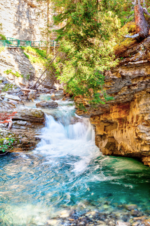 Rushing waterfall flows into the turquoise colored Johnston Canyon creek at Banff National Park in Alberta, Canada. The waters empty into the Bow River.の写真素材