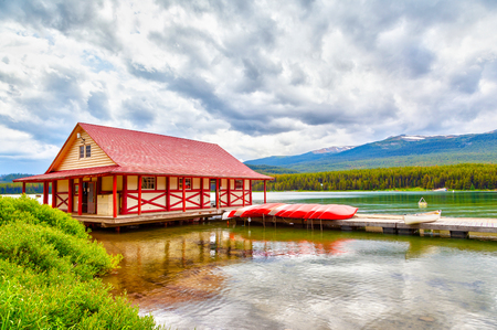 Colorful canoes lie on the boat house dock at Maligne Lake in Jasper National Park, Alberta, Canada. The lake is famous for the surrounding peaks and the three visible glaciers.のeditorial素材