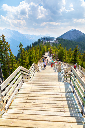 BANFF, CANADA - AUG 1, 2018: Visitors walk the wooden boardwalk on top of Sulphur Mountain between the Gondola summit and Sanson's Peak for a panoramic view of the mountain range in the Canadian Rockies of Banff National Park.のeditorial素材